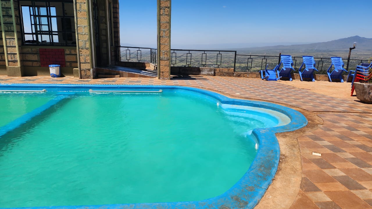 The pool deck and blue loungers, looking out over the valley to the hills beyond.