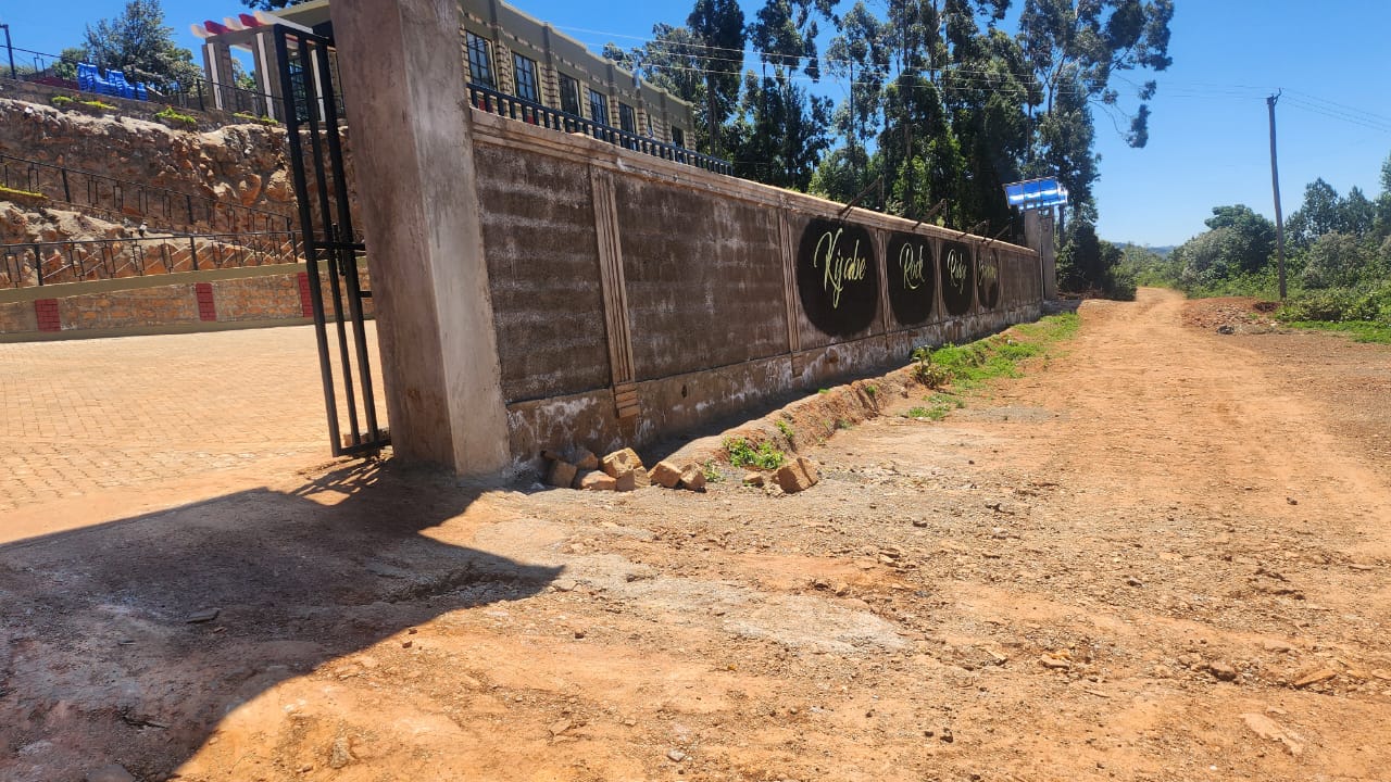 The boundary wall and entrance gate seen from the approach road.