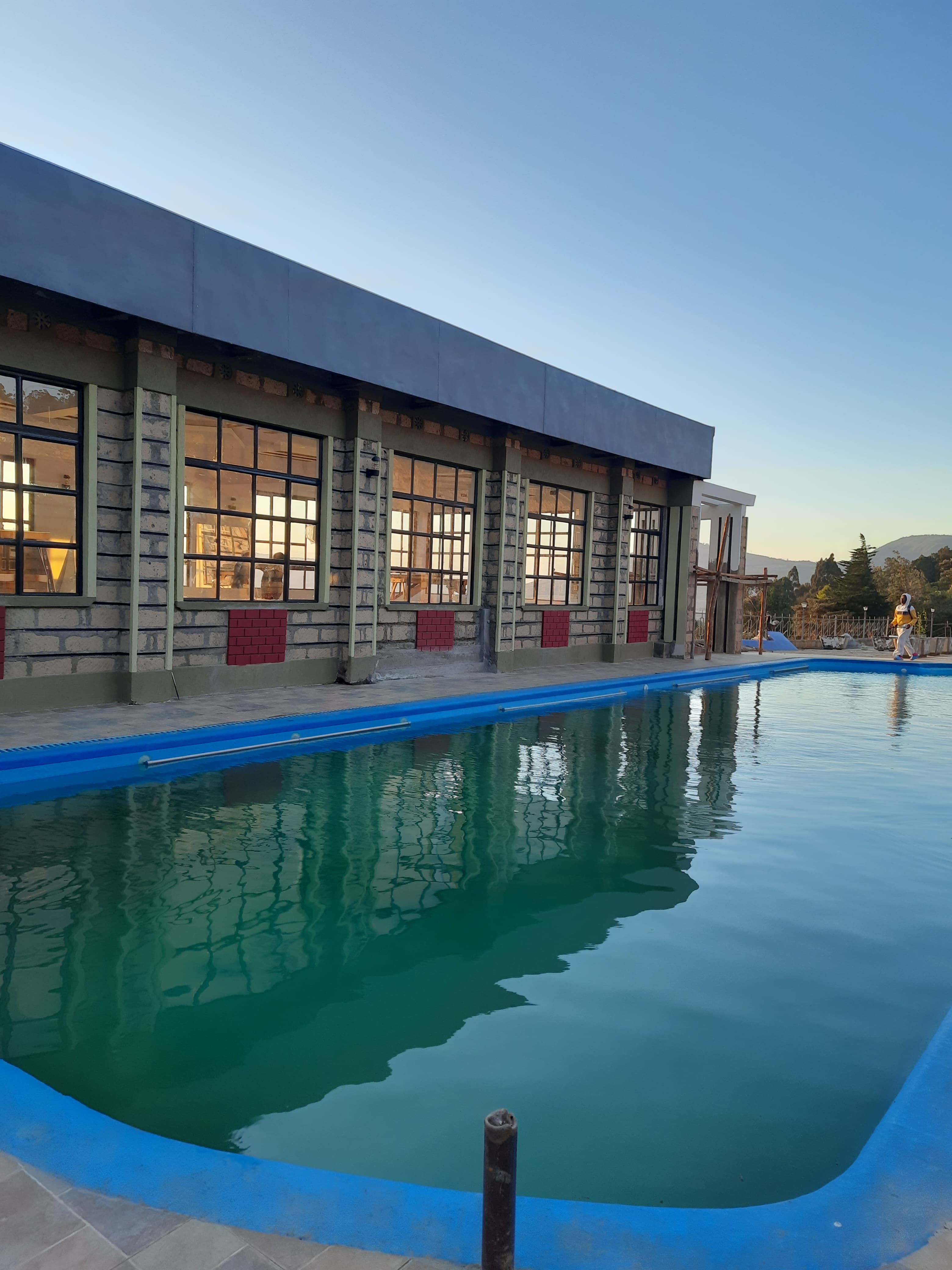 The swimming pool at dusk, reflecting the lit windows of the building alongside it.